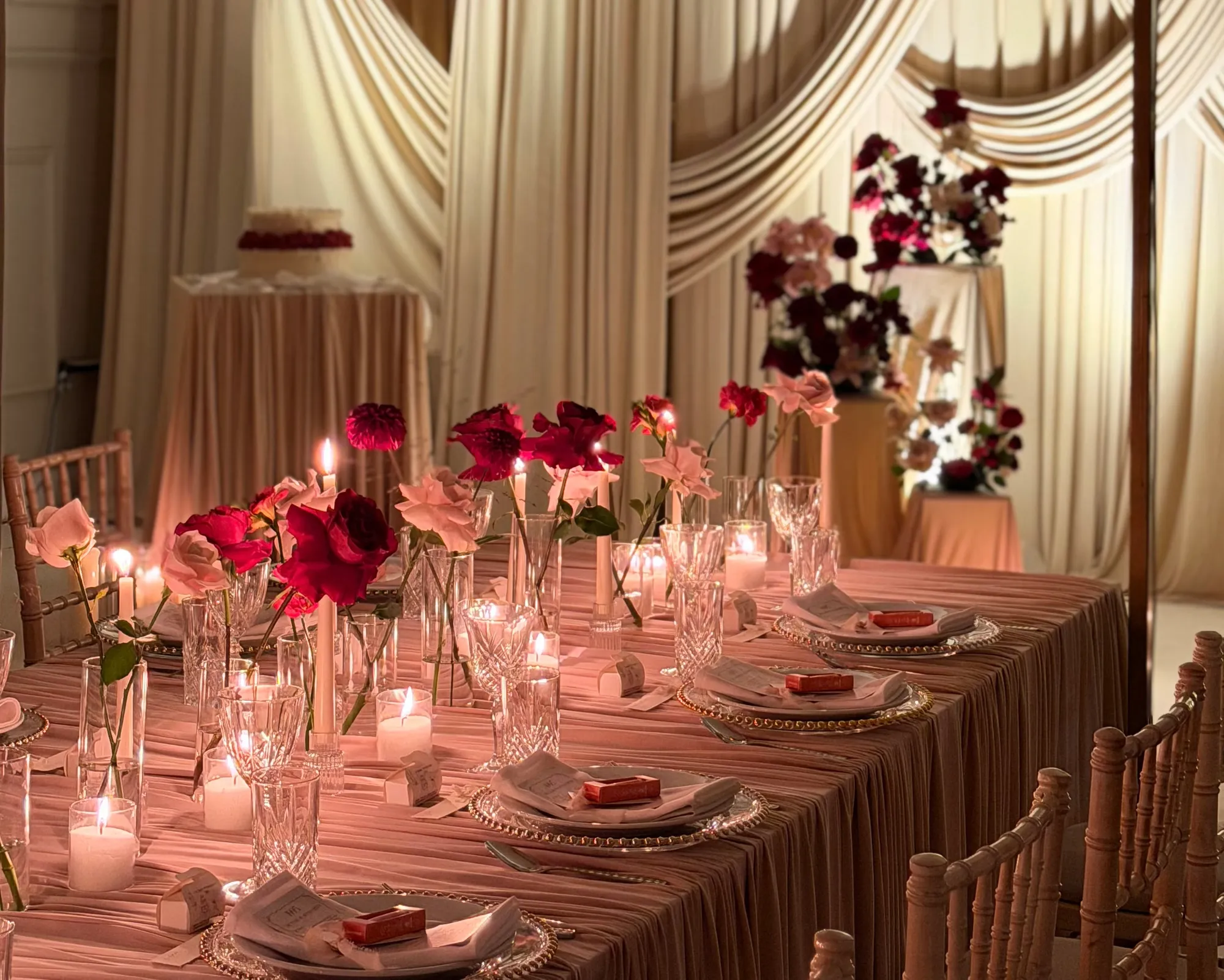 A wedding top table with floating candles in glass cylinders, red roses and orchids