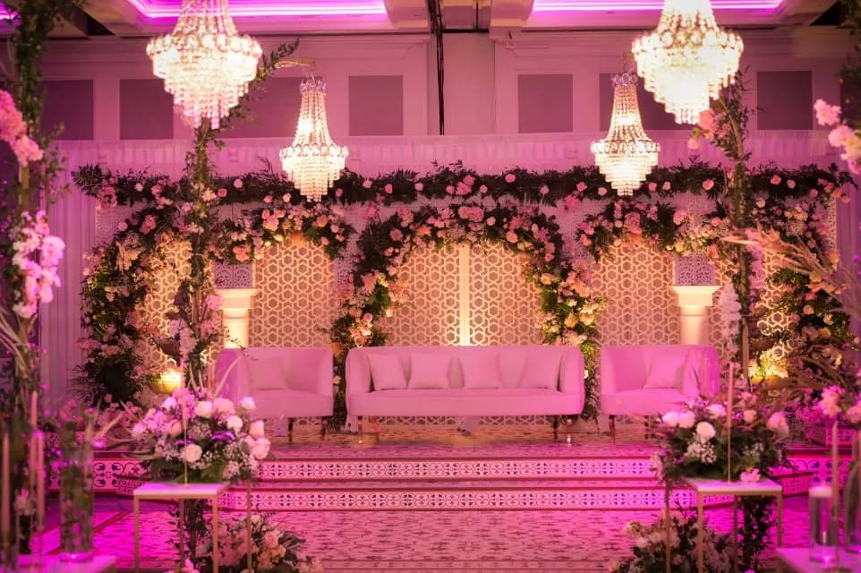 A Mehndi stage of pink-lit jharokha arches and sofas