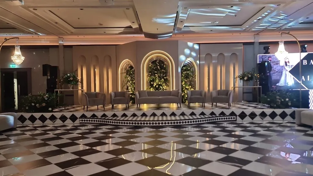 A black and white checkerboard dance floor before a lit arched stage