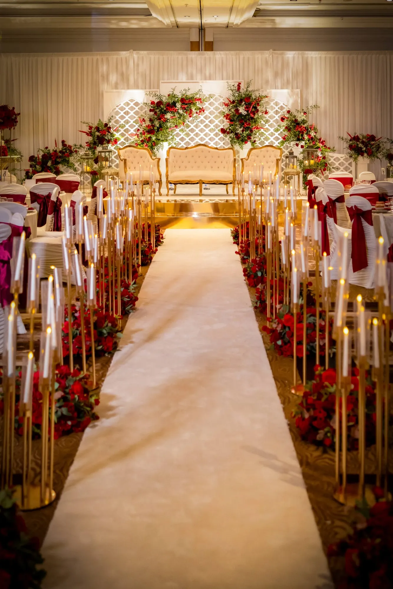 A gold walkway lined with candle pillars and flowers